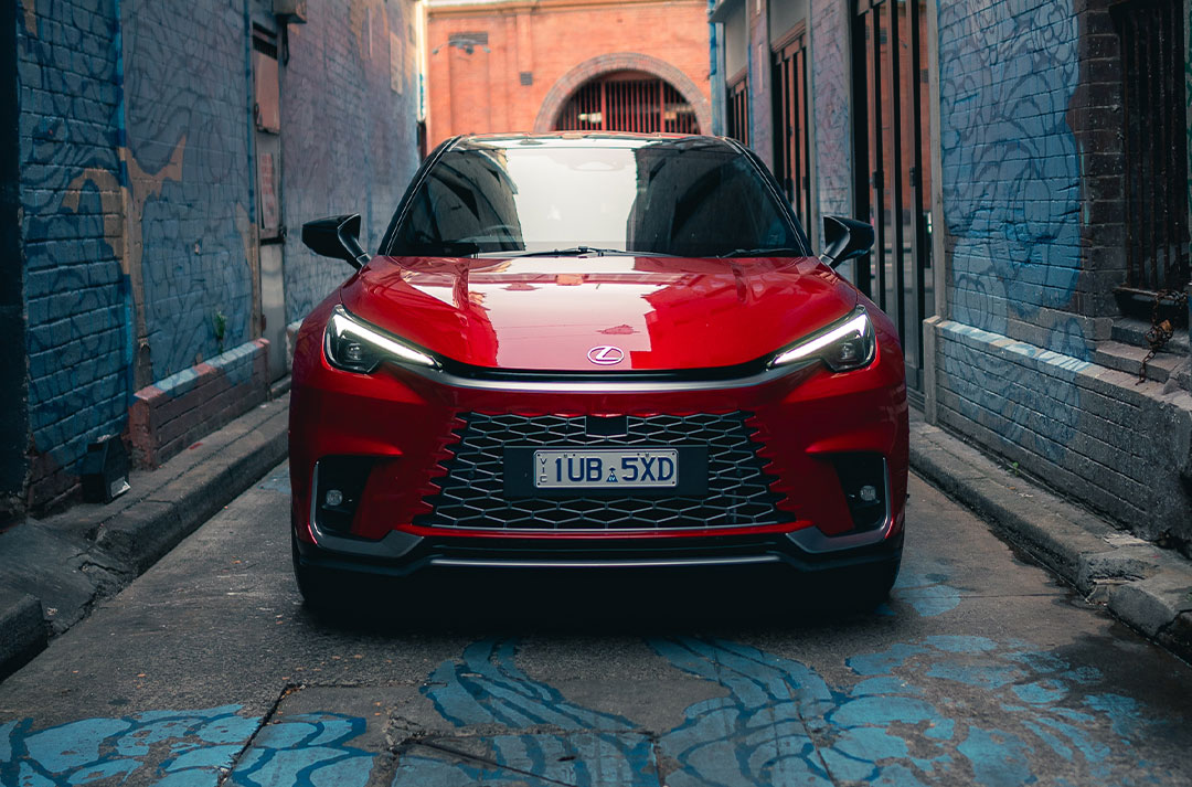 Red Lexus LBX sits in a painted alley way. 