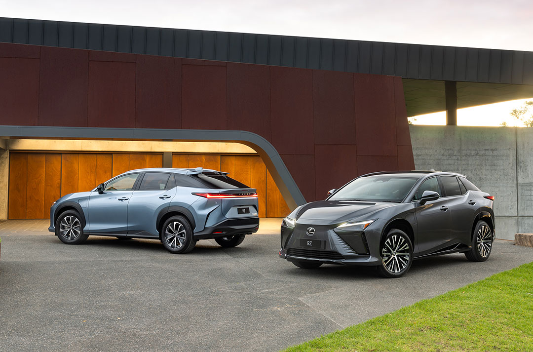 Light blue and dark grey Lexus RZ sitting parked on a concrete driveway.
