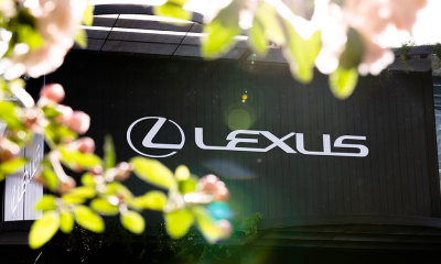 White Lexus logo and 'LEXUS' wordmark displayed on a black sign outdoors.