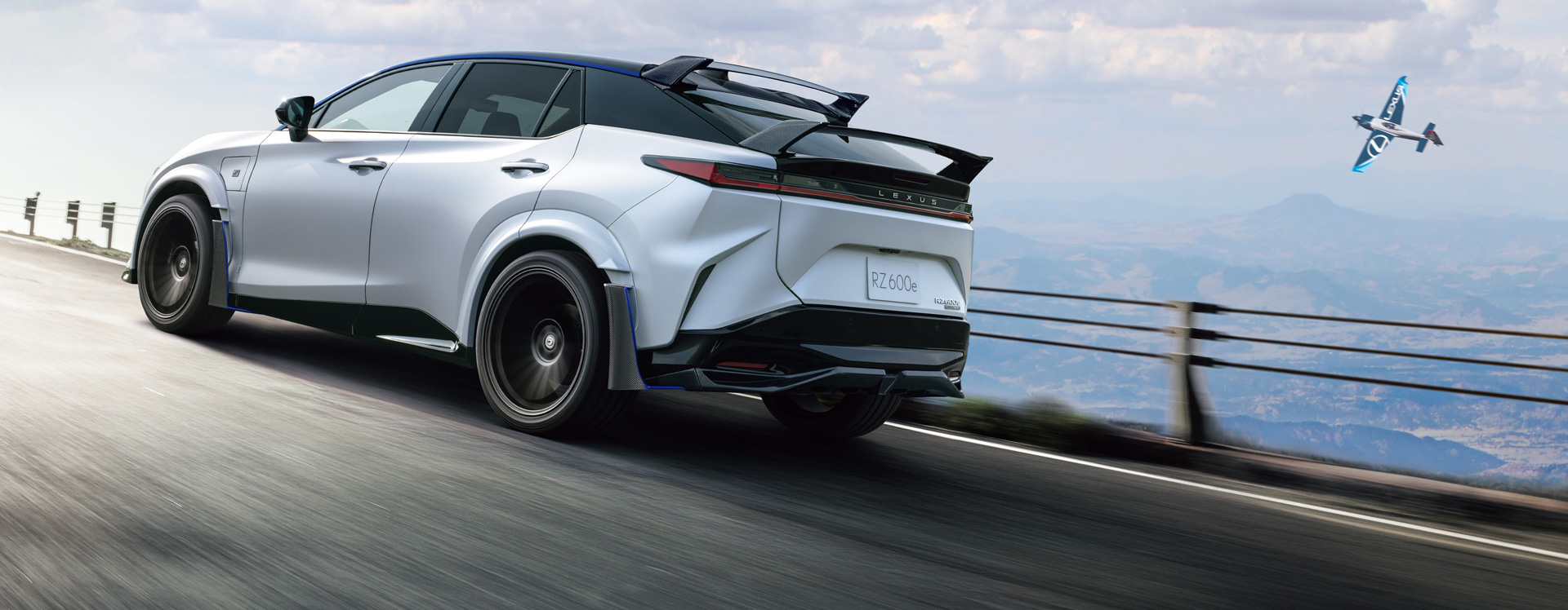 A white Lexus RZ 600e F Sport Performance driving on a mountain road.